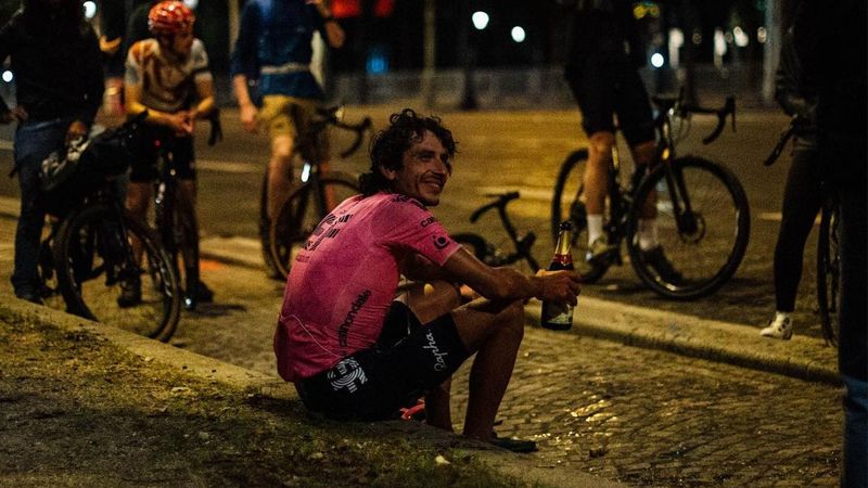 Lachlan Morton in Paris in his EF kit with a celebratory bottle of champagne on completion of his Alt Tour