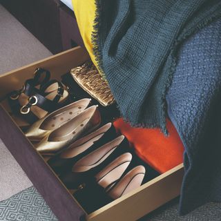 A bed with underbed storage drawers full of shoes