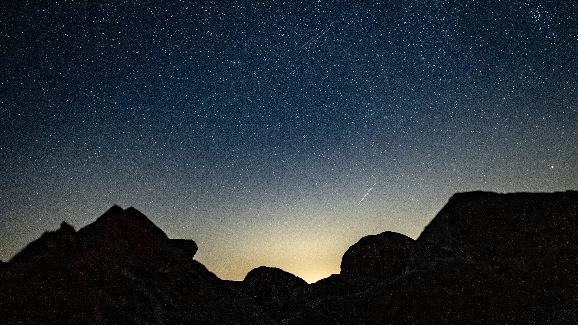 a streak of light crosses through the night sky