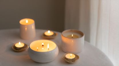 Scented candles in ceramic bowls on linen tablecloth at home