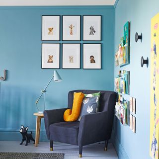 kids room with navy blue armchair and blue walls with framed wall art