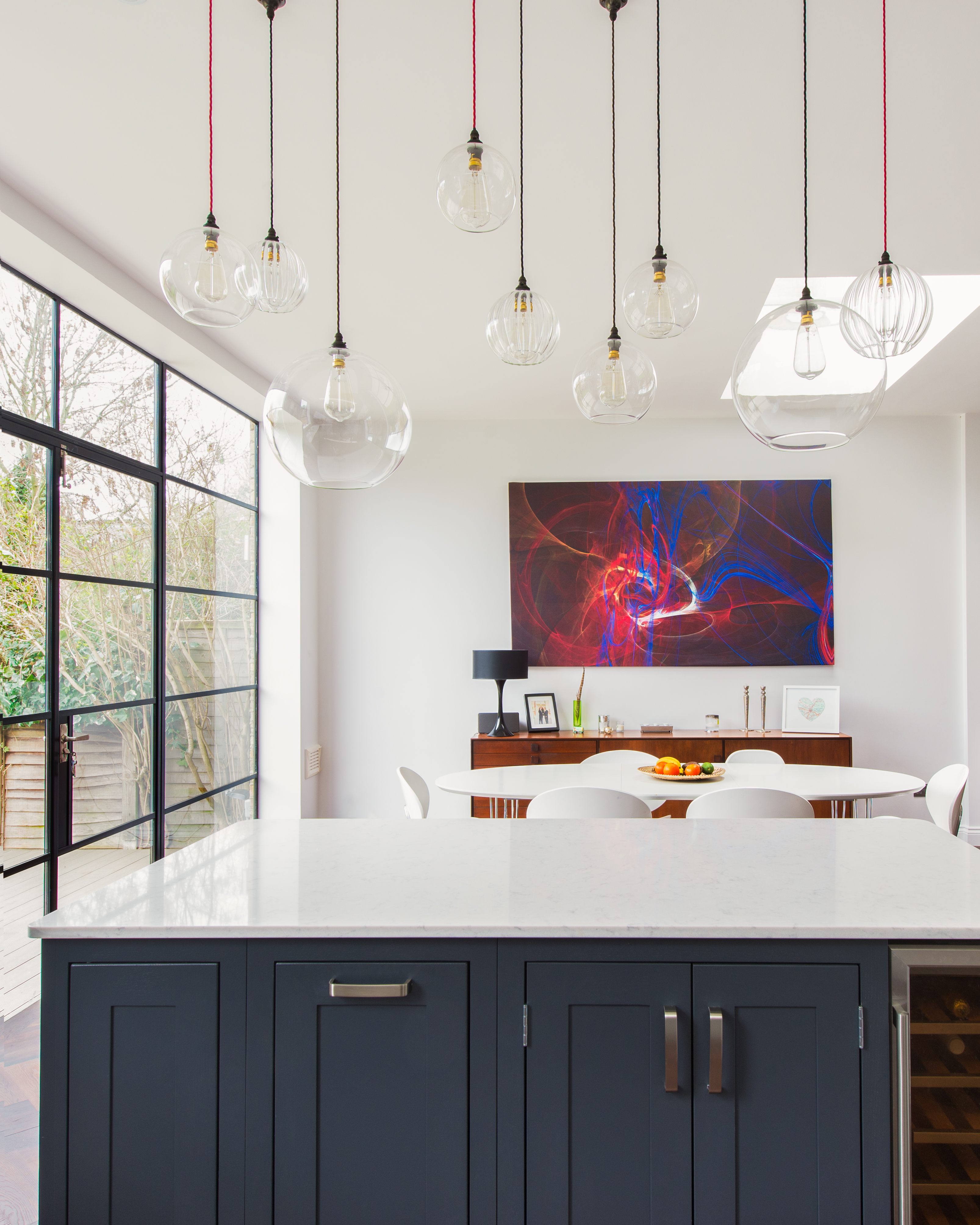 open plan kitchen dinedr with statement pendant lighting and blue interiors by fritz fryer