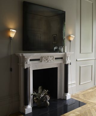 A living room wall lighting idea by Original BTC with two pleated wired wall lights placed either side of a large flat screen TV over fireplace