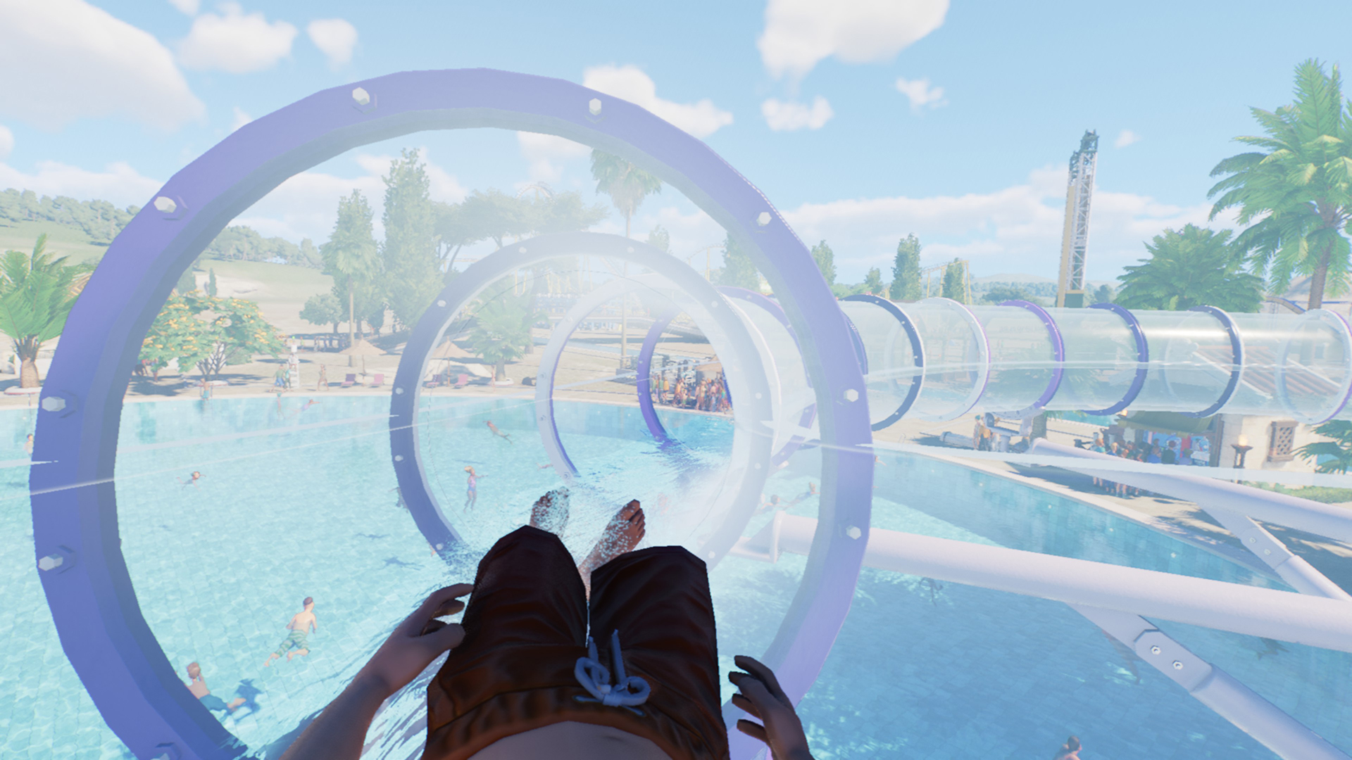 A theme park guest hurtling down a transparent flume, with a pool and tropical plants in the background.