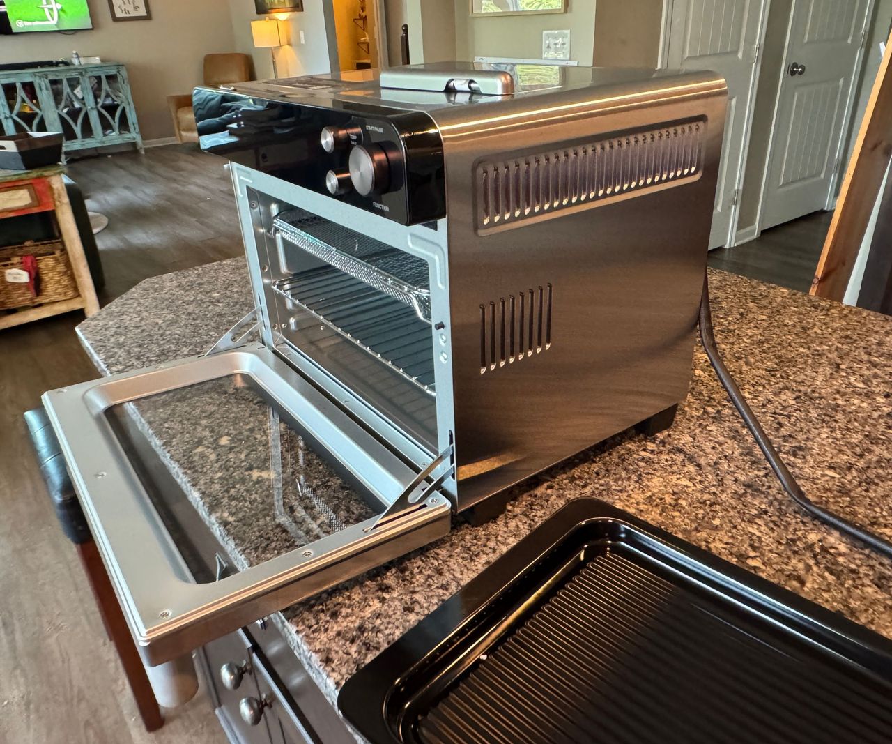 The Typhur Sync Air Fryer Oven on a granite worktop with the door open