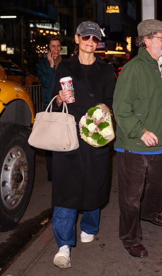 katie homles wears a black topcoat and white sneakers