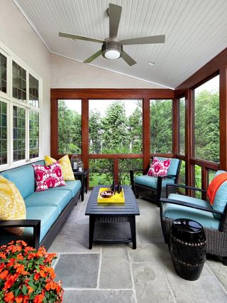 Wood framed sunroom with two blue couches facing each other and ceiling fan installed