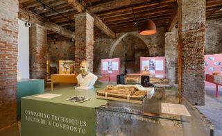 Exhibition called "Comparing Techniques", set in a room with exposed brickwork and wood beams