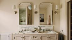 A double sink bathroom vanity with two mirrors, and three wall sconces.