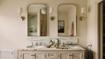 A double sink bathroom vanity with two mirrors, and three wall sconces. 