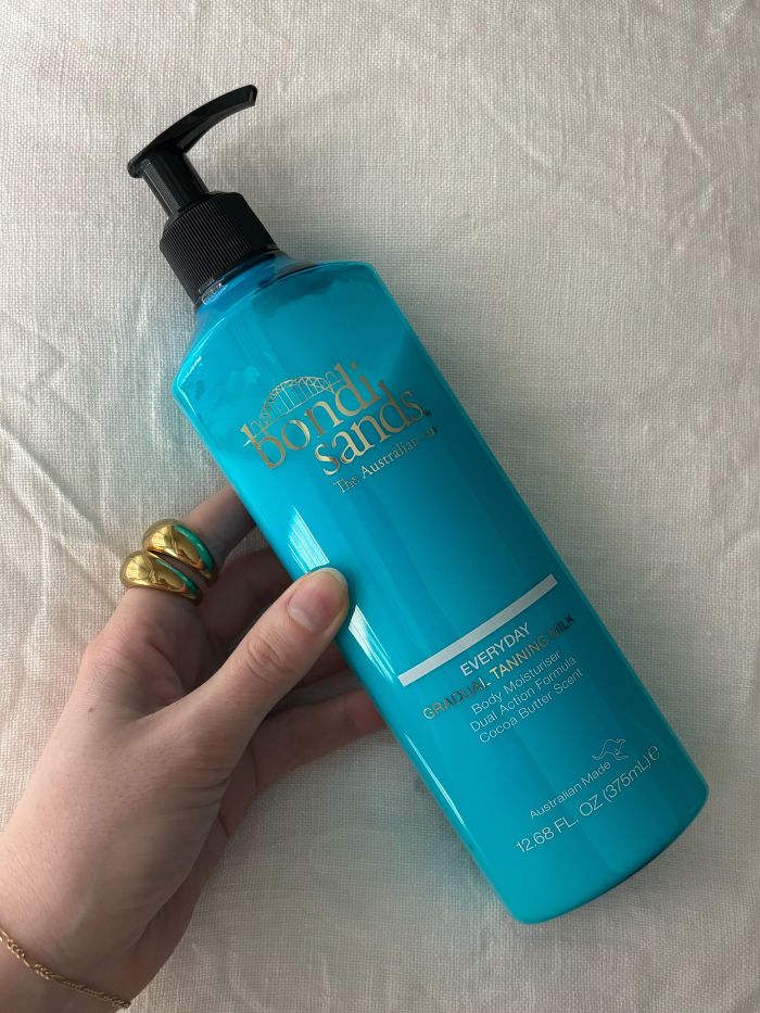 Die stellvertretende Beauty-Redakteurin Grace Lindsay hält die Bondi Sands Everyday Gradual Tanning Milk in der Hand