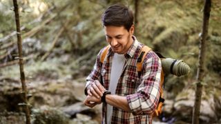 Hiker checking GPS watch in forest