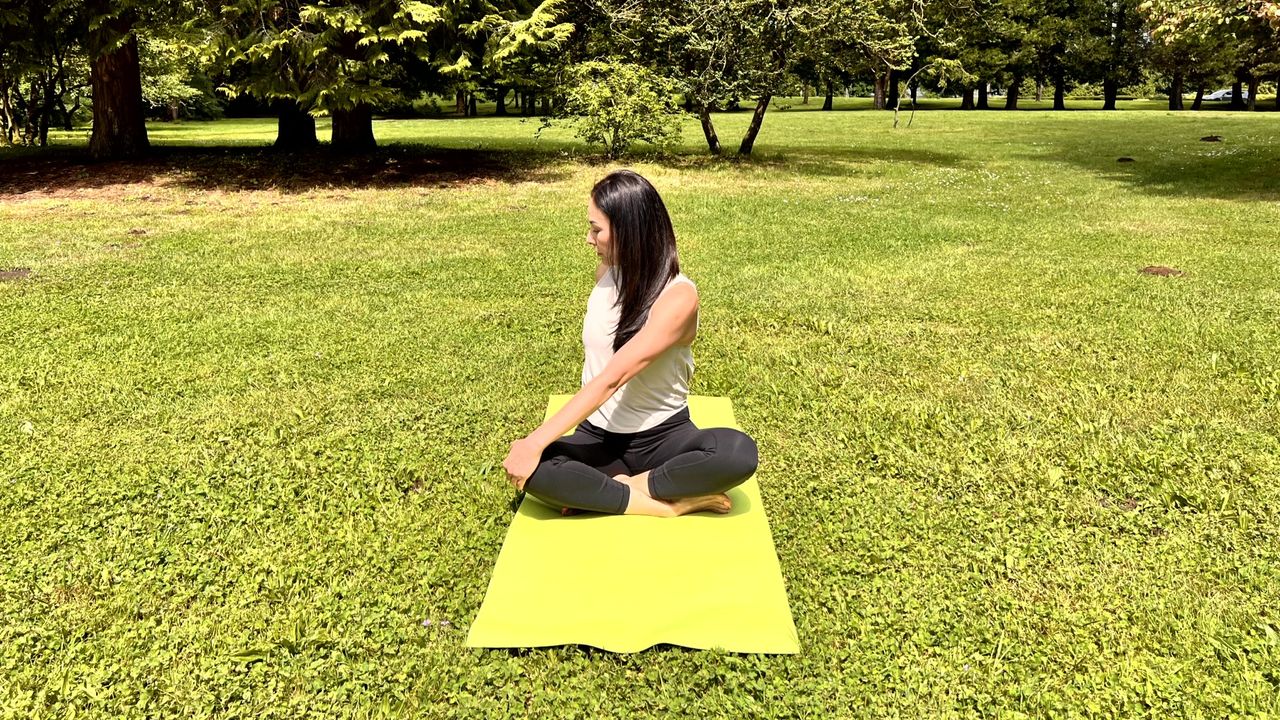 Woman in yoga pose on a mat in her garden