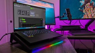 The Razer Laptop Cooling Pad on a desk, showing the ASUS ProArt P16 (2024) laptop attached and the RGB lighting enabled.