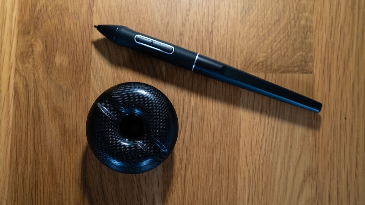 Pen and spare nibs for a Huion Kamvas Pro 24 (4K) drawing tablet on a wooden surface