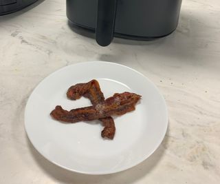 Bacon on a plate in front of the Cosori Pro LE Air Fryer.