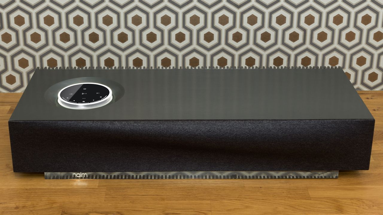 Naim Mu-so 2 on wooden desk with hexagonal wallpaper background