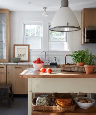 A modern rustic kitchen with a large white light fixture and wooden island