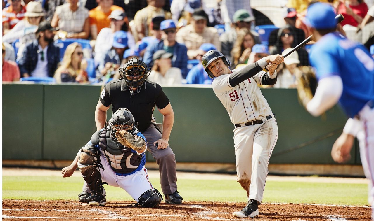 Player batting a pitch at a baseball game with a catcher in the background.