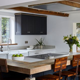 White kitchen with wooden worktop on island and ceiling beams