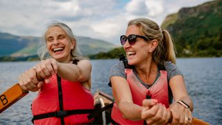 Two women holding oars on boat wearing life jackets