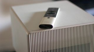 a white square projector with a remote control resting on it