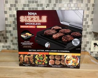 Ninja Sizzle Smokeless Indoor Grill and Sizzle in boxed packaging on wood effect countertop