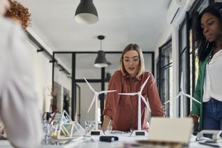 Ethical businesses: Businesswomen having a meeting in office with wind turbine models on table