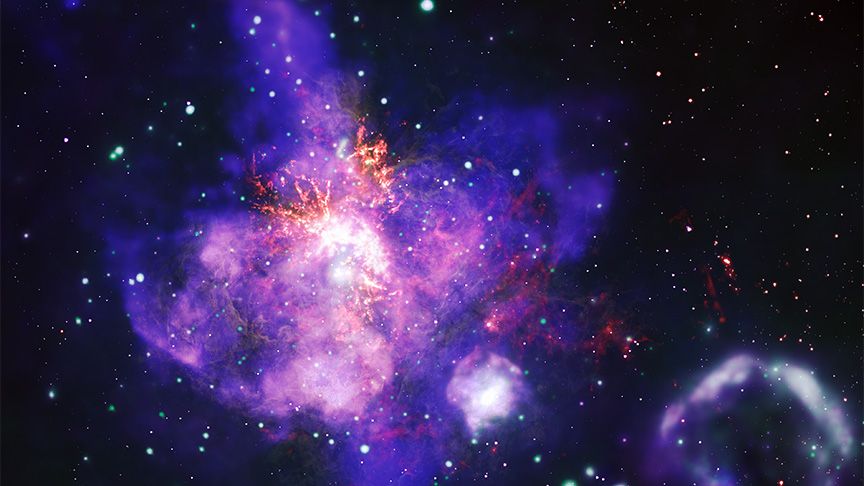  a highly detailed composite image of a star-forming region of space known as 30 Doradus, shaped like a bouquet, or a maple leaf. 30 Doradus is a powerful stellar nursery. In 23 days of observation, the Chandra X-ray telescope revealed thousands of distinct star systems. Chandra data also revealed a diffuse X-ray glow from winds blowing off giant stars, and X-ray gas expelled by exploding stars, or supernovas. In this image, the X-ray wind and gas takes the shape of a massive purple and pink bouquet with an extended central flower, or perhaps a leaf from a maple tree. The hazy, mottled shape occupies much of the image, positioned just to our left of center, tilted slightly to our left. Inside the purple and pink gas and wind cloud are red and orange veins, and pockets of bright white light. The pockets of white light represent clusters of young stars. One cluster at the heart of 30 Doradus houses the most massive stars astronomers have ever found. The hazy purple and pink bouquet is surrounded by glowing dots of green, white, orange, and red. A second mottled purple cloud shape, which resembles a ring of smoke, sits in our lower righthand corner.