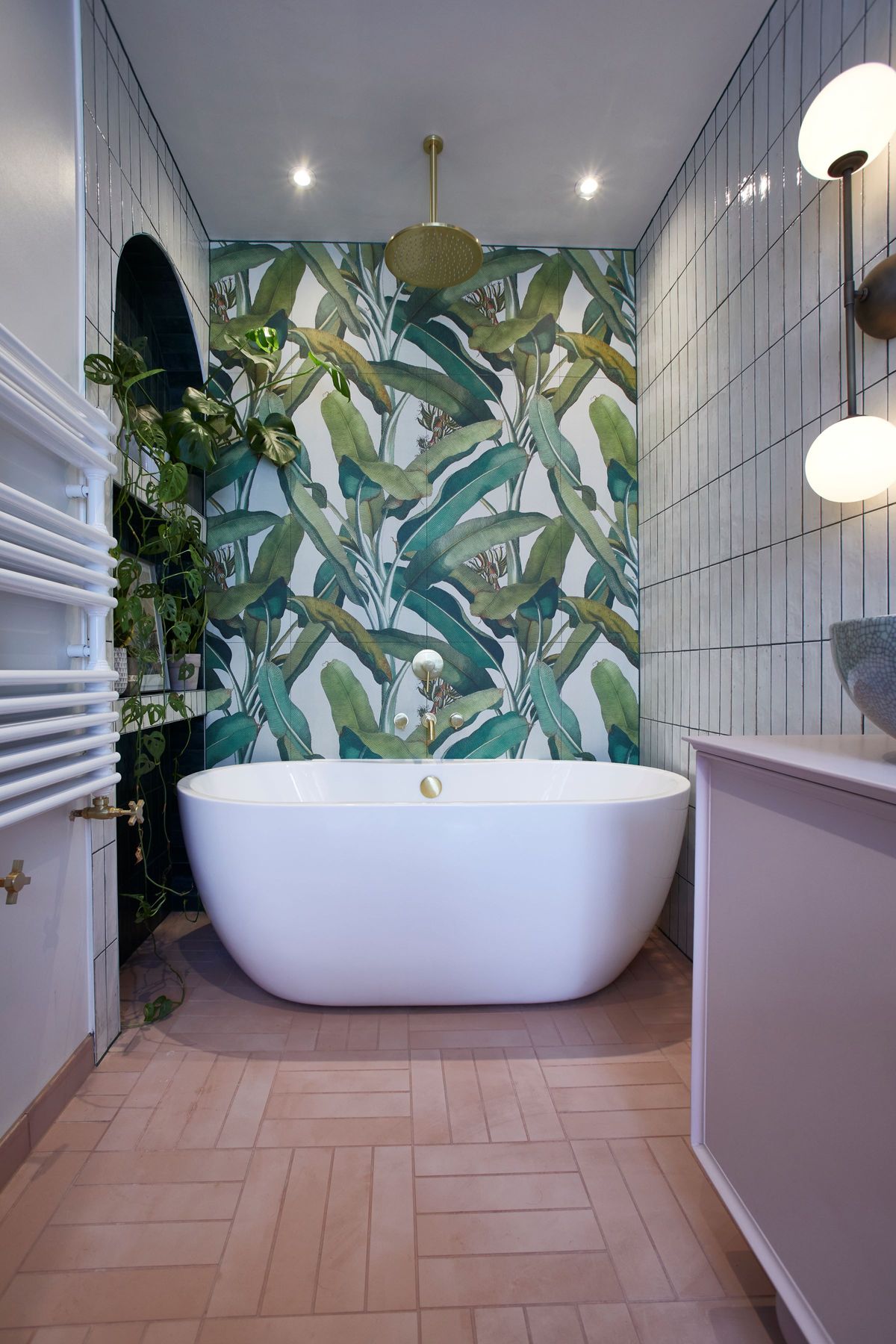 The bathroom has a white bath and a green mural wall