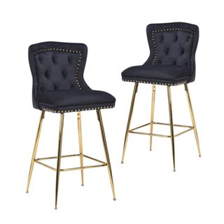 Two curved black velvet chairs with tufted button backs and gold legs on each