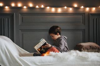 How to help your kid sleep on Christmas eve featuring a child reading a book on his bed