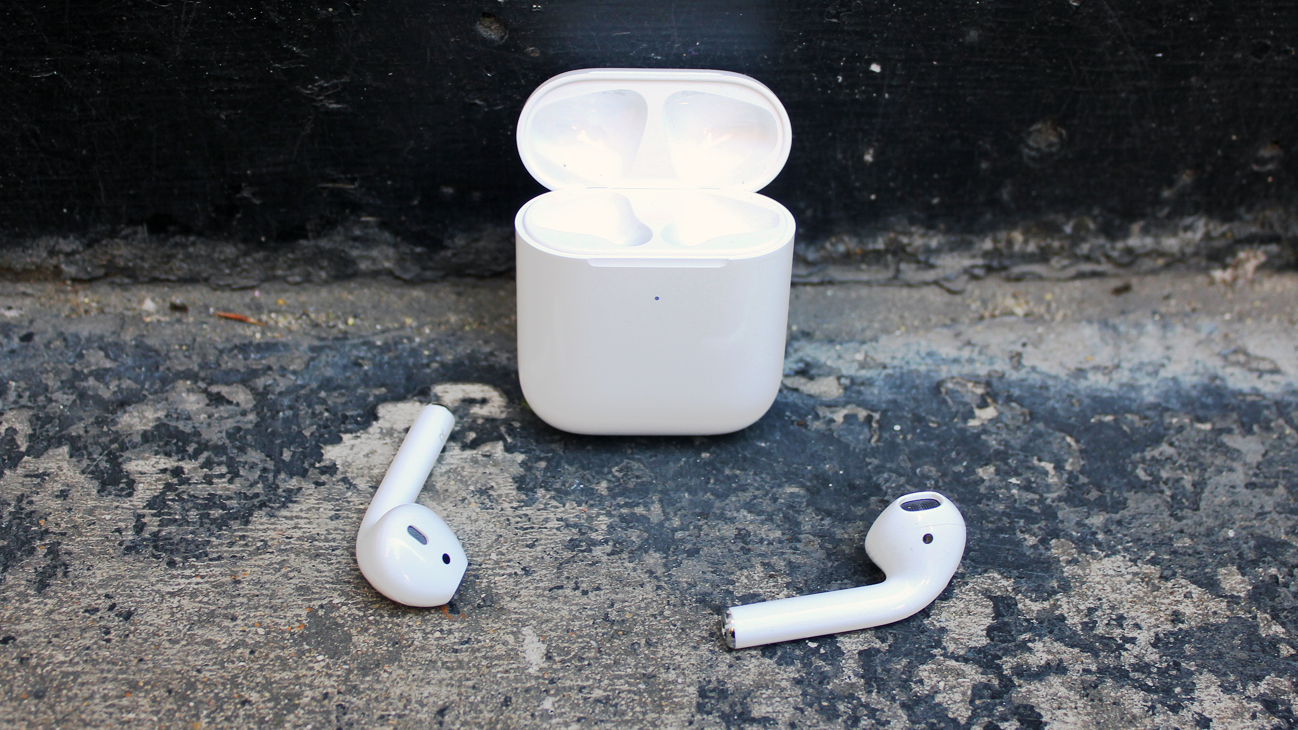 2019 Apple Airpods buds stacked in front of the charging case.