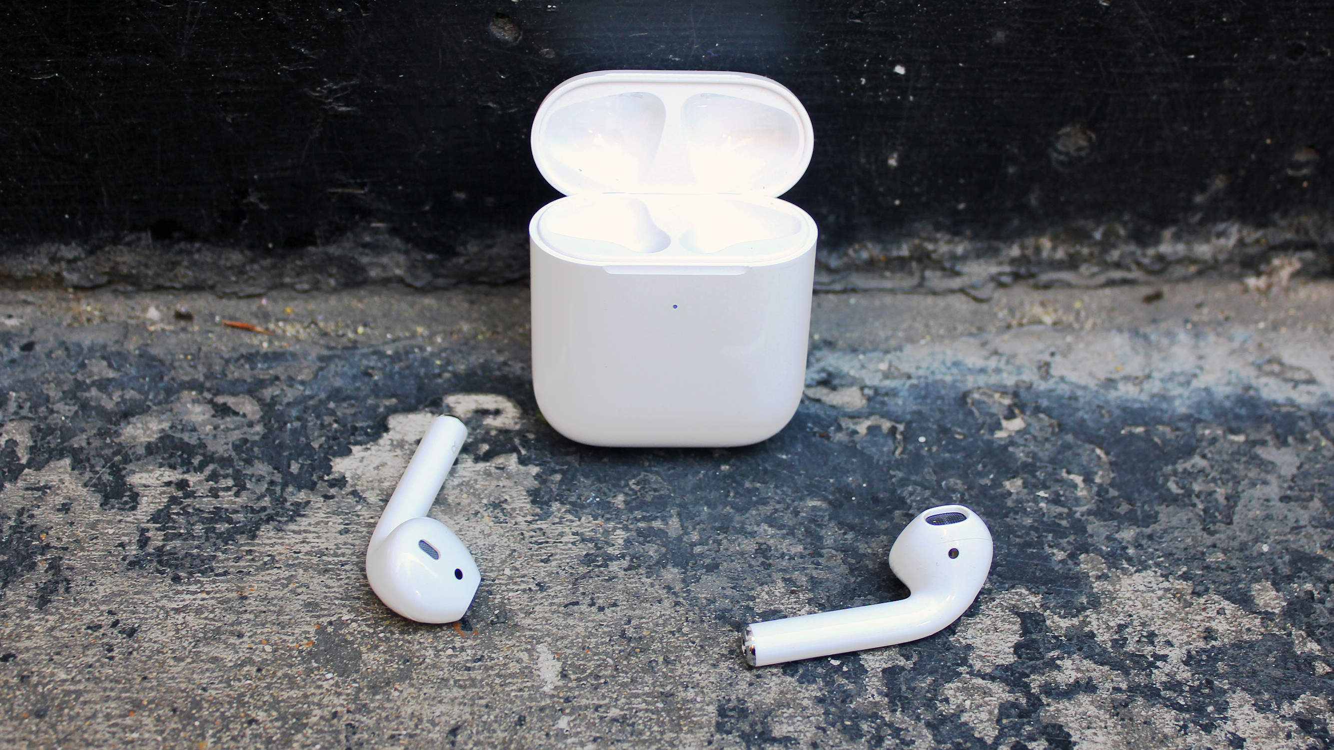 The Apple Airpods 2019 buds laid out in front of their charging case.