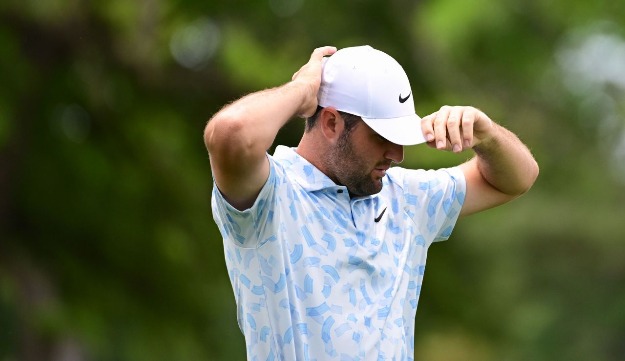 Scottie Scheffler readjusts his hat walking down the fairway