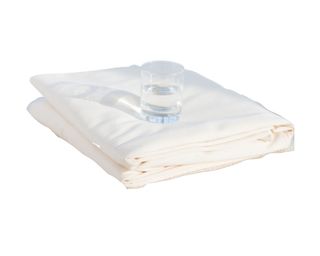 Avocado Organic Waterproof Mattress Protector, folded with a glass of water on top
