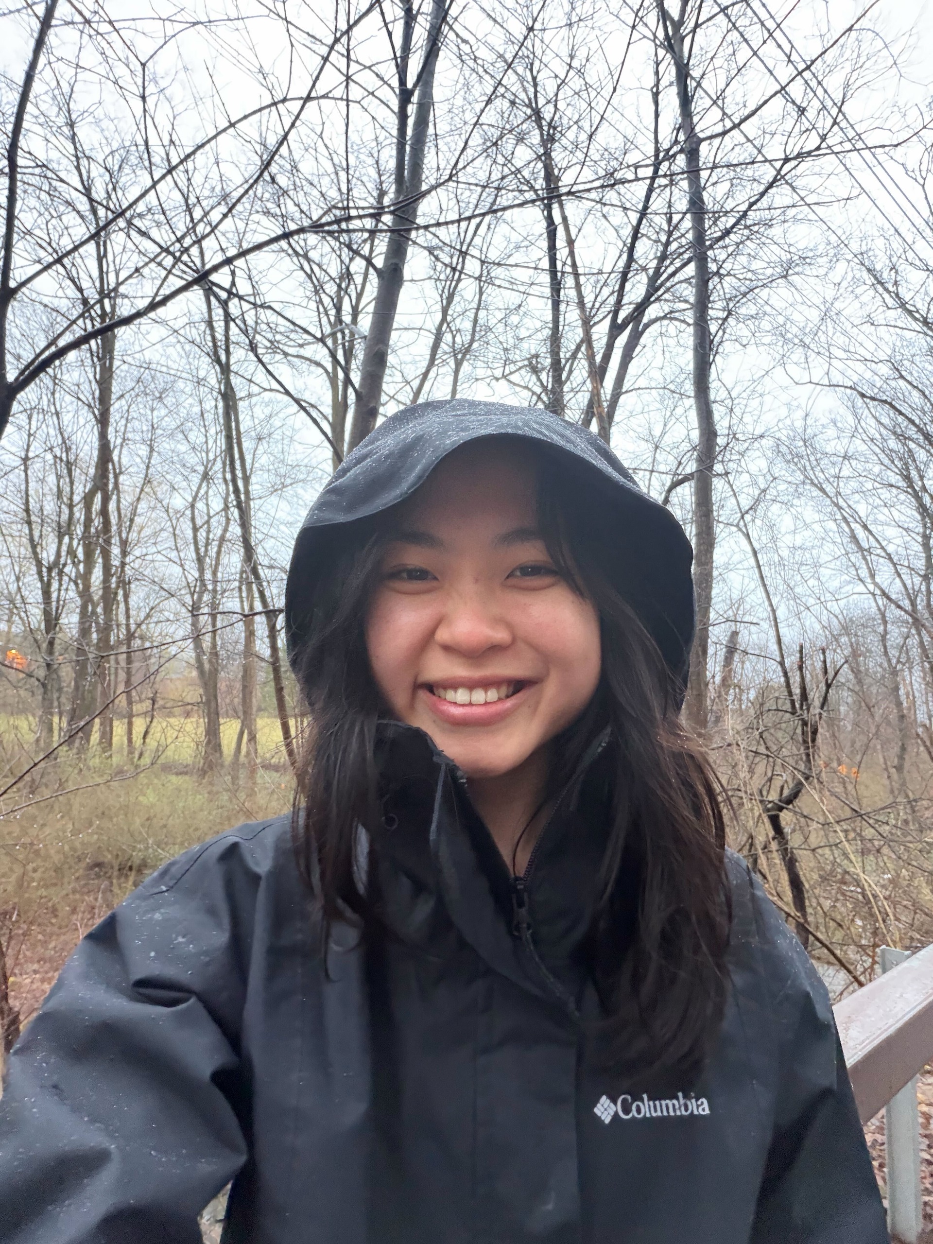 Young woman wearing black anorak smiling to camera outside in a rural area