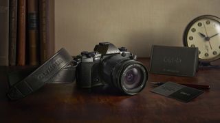 Lifestyle image of an Olympus OM-D E-M5 Mark II Titanium on a table, in front of old books and a clock