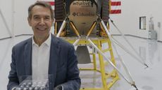 Jeff Koons in front of Intuitive Machines lunar module, holding his Jeff Koons: Moon Phases sculptures in a clear cubed case