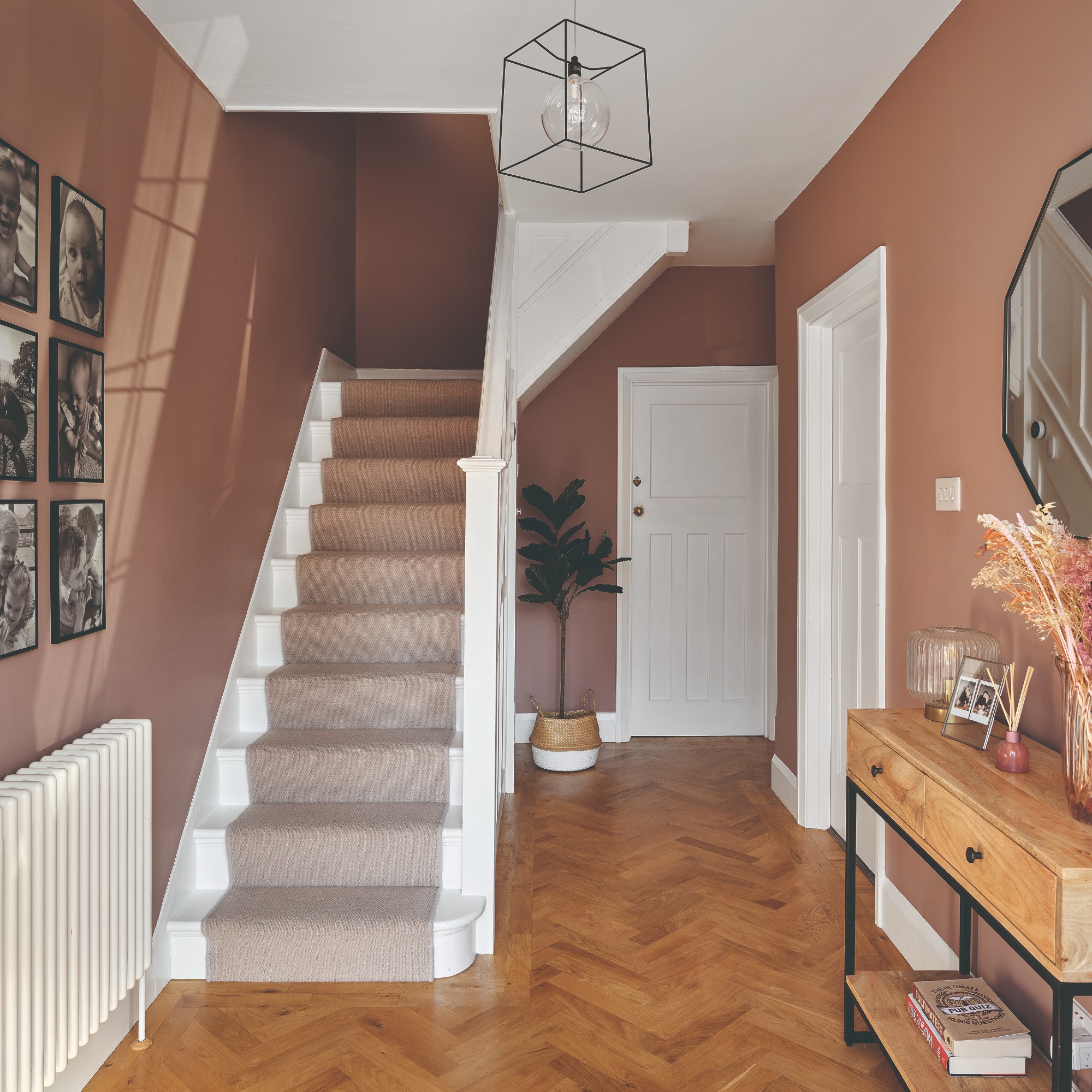A hallway painted in a soft brown shade with a photography gallery wall and a staircase