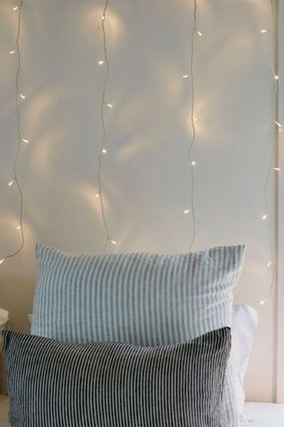 Lights4fun Warm White LED Curtain Lights behind bedroom wall with curtains leaning