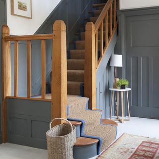 hallway with wooden staircase rug on floor and basket