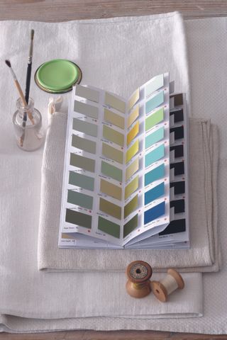 A color chart laying open on green and blue page on some fabric samples