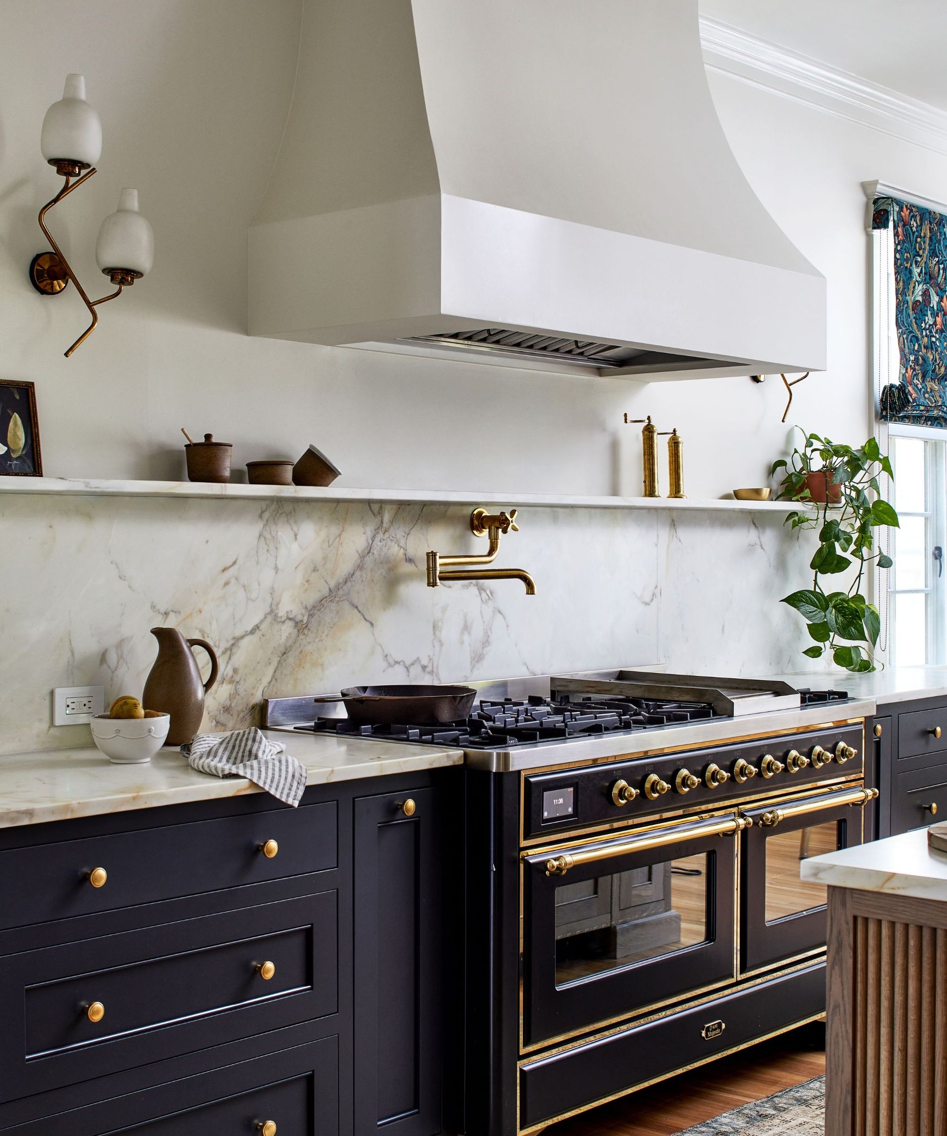 A blue and white kitchen with a classic black and brass range cooker and a plastered extractor hood