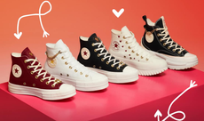 A selection of sneakers available from Converse placed on a pink box with love heart illustrations.