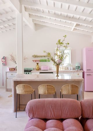 Kitchen-diner with neutral island, pink Smeg fridge and mauve sofa