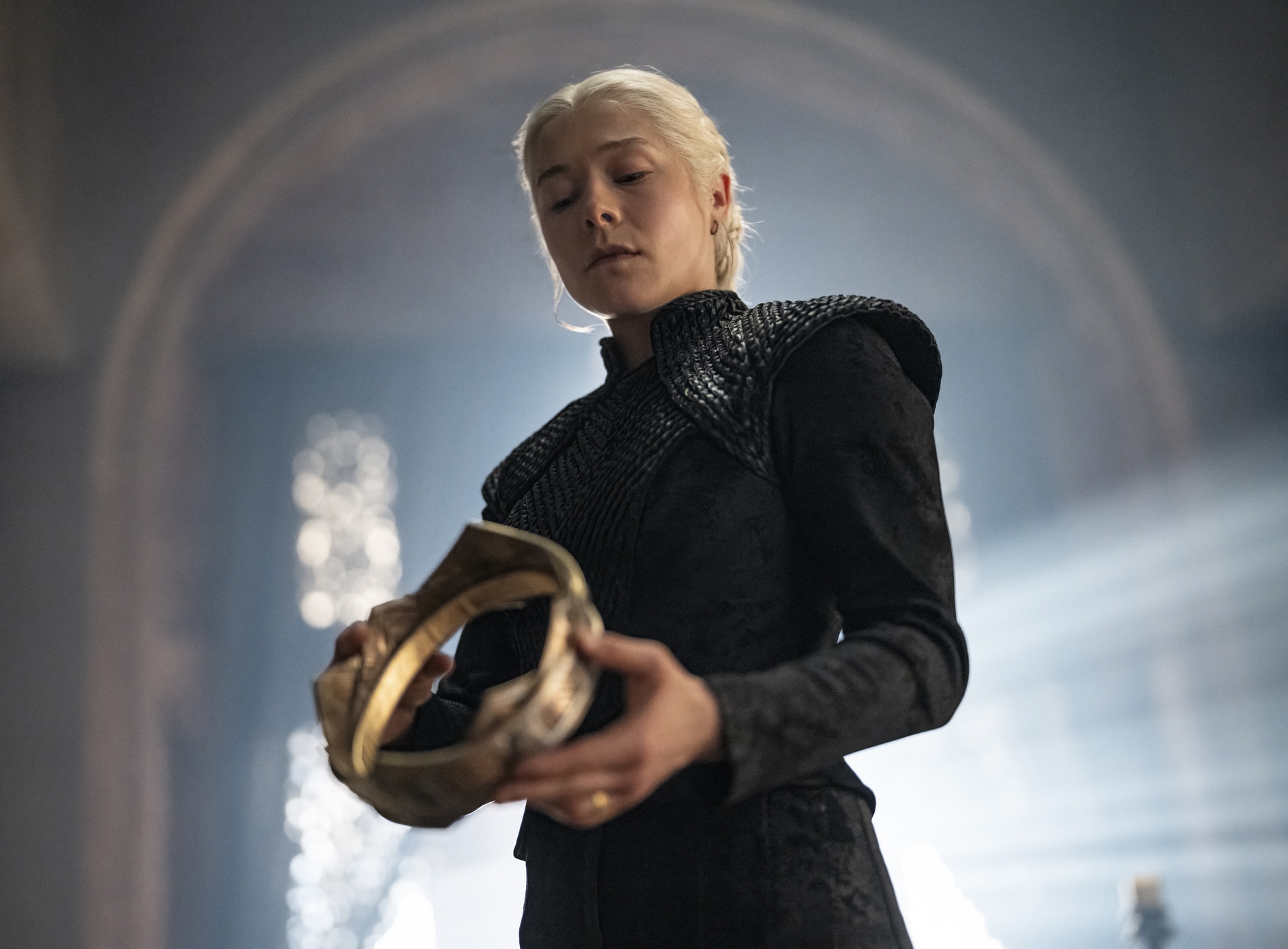 Emma D'Arcy as Rhaenyra, looking down while holding a golden crown, in a first-look image from 'House of the Dragon' season 3.