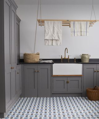 utility room with grey cupboards, patterned flooring and ceiling mounted drying rack