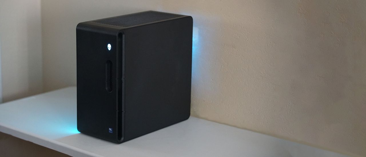 An angled wide-angle view of the Alienware Aurora gaming desktop on a desk in a darkened room