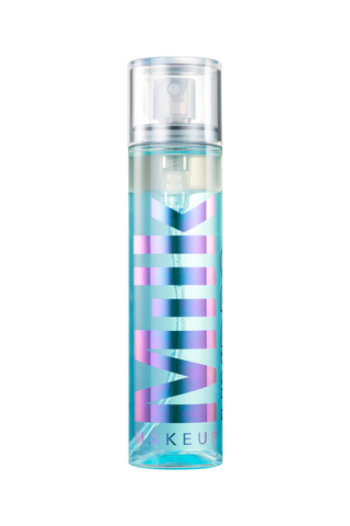 A transparent blue spray bottle of Milk Makeup setting spray against a white background.